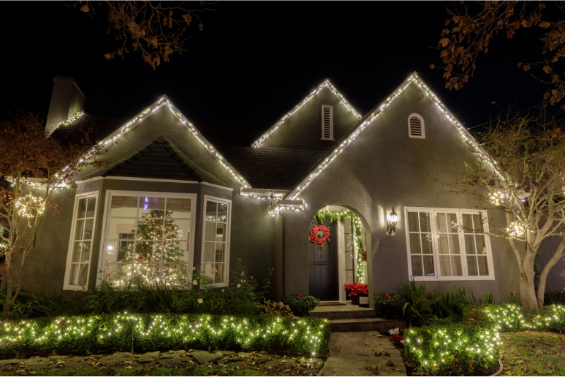 Residential Christmas light installation on a home with a wreath and lit walkway
